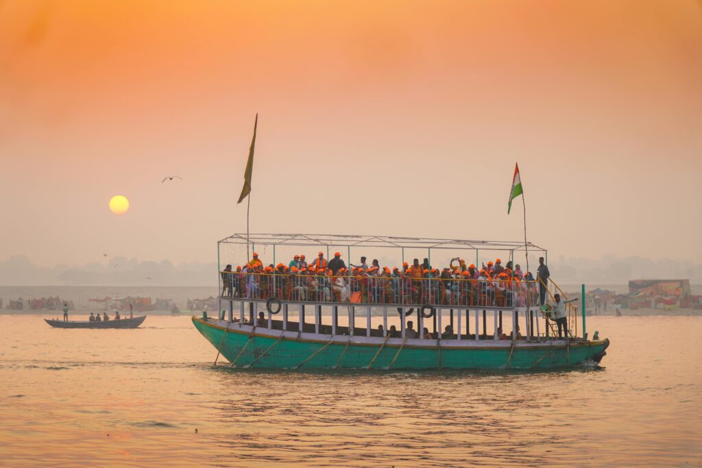 A crowded boat on the Ganges River at sunset in Varanasi, India, showcasing vibrant religious and cultural life.
