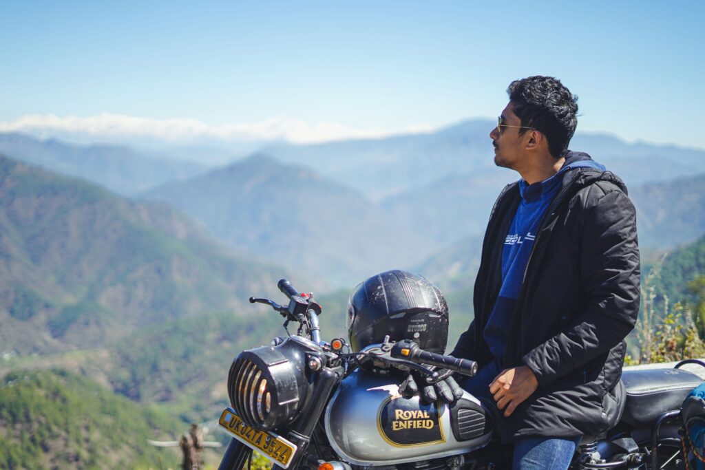 A man on a Royal Enfield enjoys a scenic mountainous view, capturing freedom and adventure.